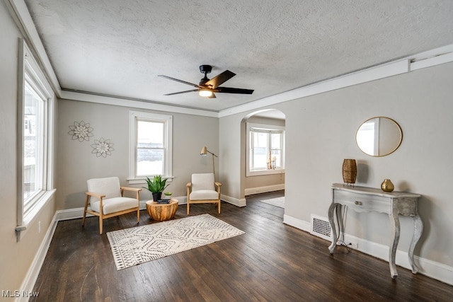 living area featuring ceiling fan, dark hardwood / wood-style flooring, a healthy amount of sunlight, and a textured ceiling