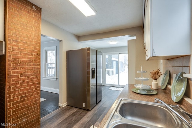 kitchen with a textured ceiling, stainless steel fridge, sink, and dark wood-type flooring