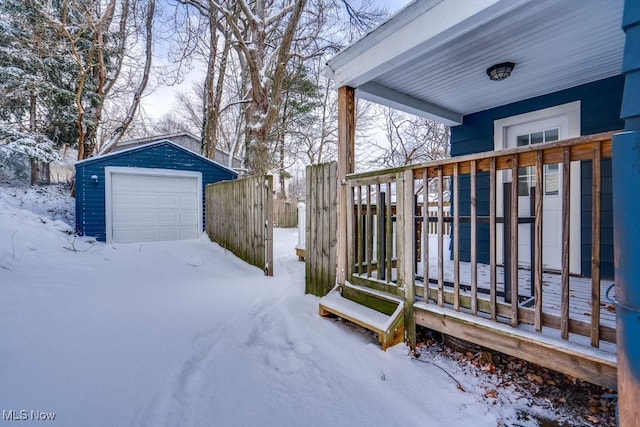 snow covered deck featuring a garage and an outbuilding