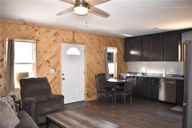 living room featuring a ceiling fan, dark wood-style flooring, and wood walls