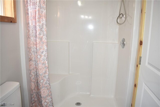 bathroom featuring toilet and a shower with shower curtain