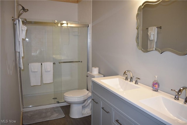full bathroom with double vanity, toilet, a shower stall, and a sink