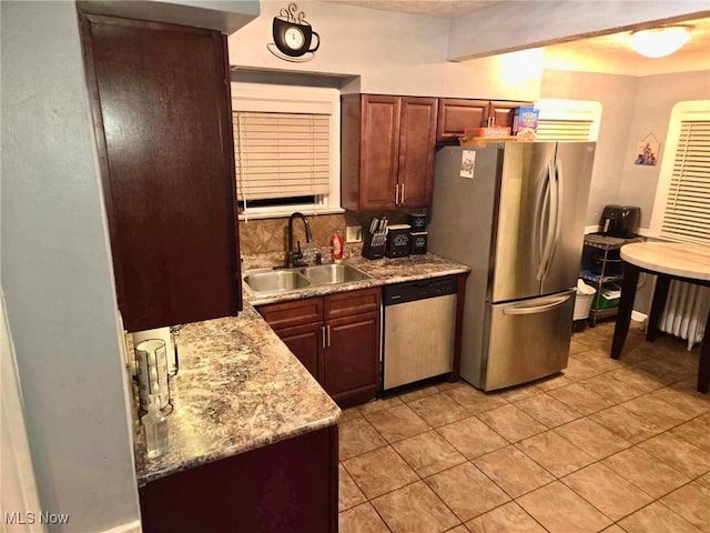 kitchen featuring backsplash, sink, light tile patterned floors, appliances with stainless steel finishes, and light stone counters