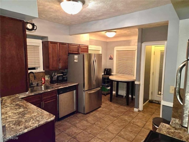 kitchen featuring sink, decorative backsplash, a textured ceiling, radiator heating unit, and stainless steel appliances