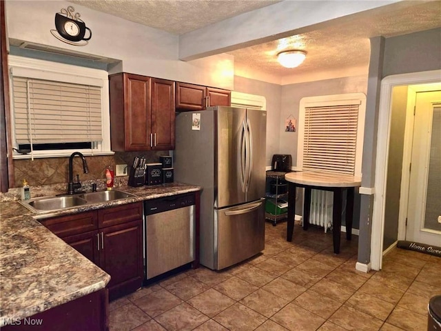 kitchen featuring sink, radiator heating unit, stainless steel appliances, backsplash, and tile patterned floors