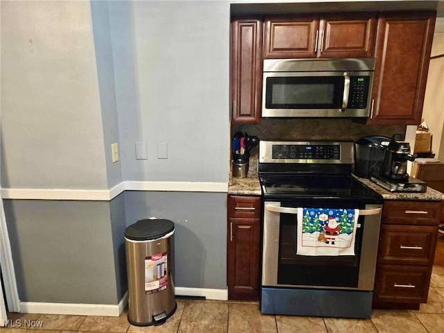 kitchen with decorative backsplash, light stone countertops, light tile patterned floors, and stainless steel appliances