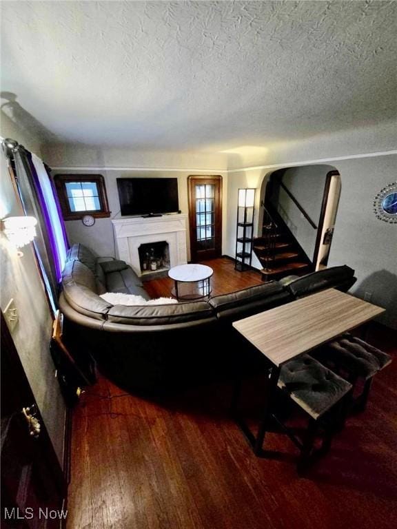 living room featuring hardwood / wood-style flooring, a textured ceiling, and a tiled fireplace