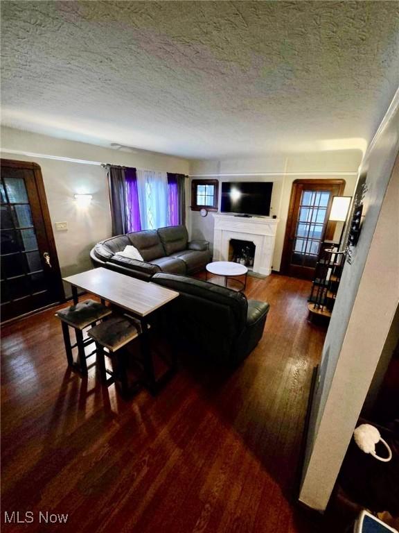 living room with a textured ceiling and dark hardwood / wood-style flooring