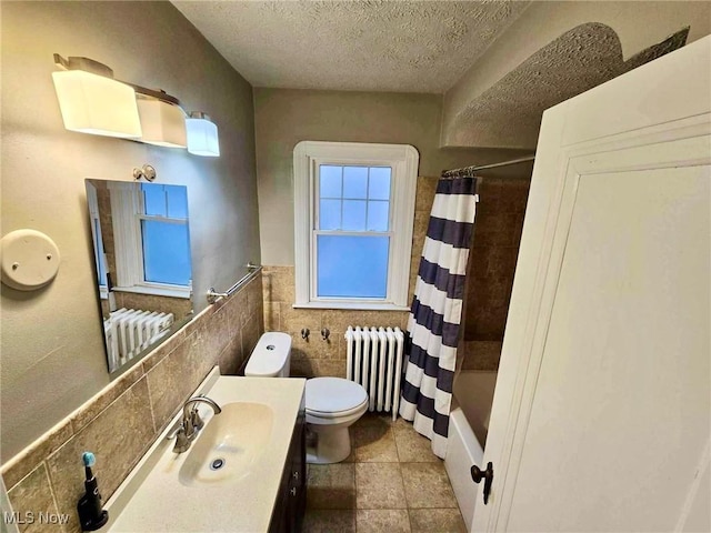 full bathroom featuring radiator heating unit, shower / bath combo, a textured ceiling, toilet, and tile walls