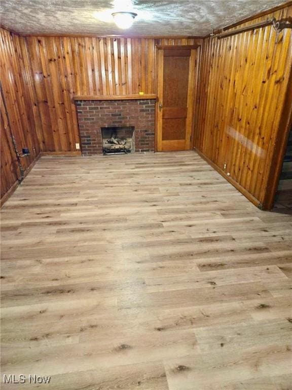 unfurnished living room featuring light hardwood / wood-style floors and a brick fireplace