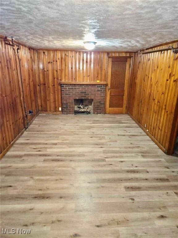 unfurnished living room featuring a textured ceiling, a fireplace, and light hardwood / wood-style flooring