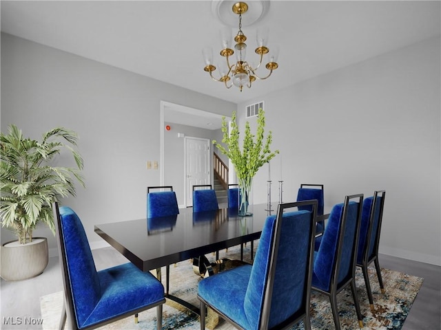 dining space with hardwood / wood-style floors and an inviting chandelier