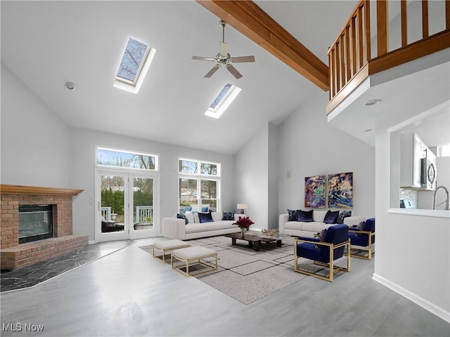 living room with high vaulted ceiling, a skylight, ceiling fan, a fireplace, and beamed ceiling