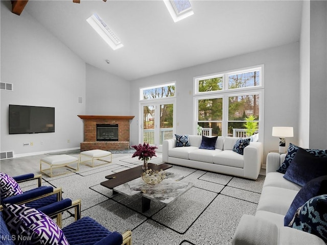 living room featuring a brick fireplace, a skylight, and high vaulted ceiling