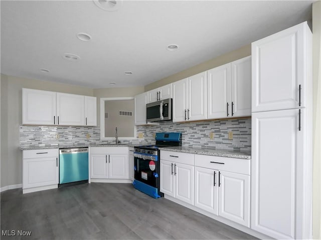 kitchen with light stone countertops, sink, stainless steel appliances, tasteful backsplash, and white cabinets