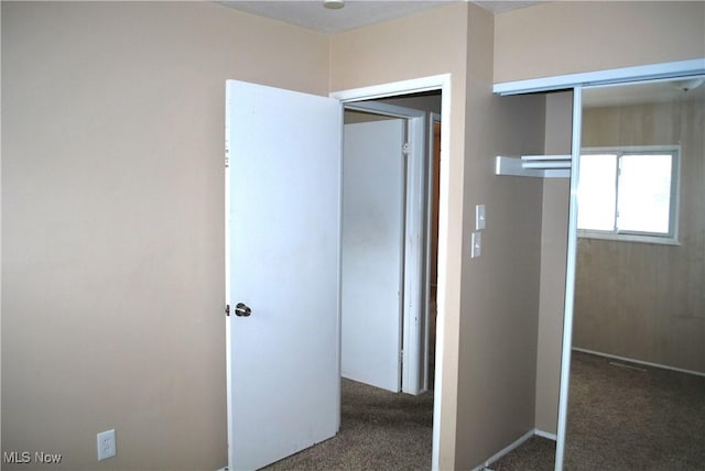 unfurnished bedroom featuring a closet and dark colored carpet