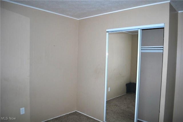 unfurnished bedroom featuring dark carpet and a closet