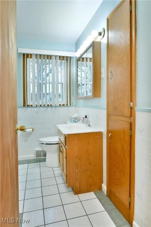 bathroom with tile patterned flooring, vanity, toilet, and tile walls