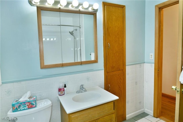 bathroom with tile patterned floors, vanity, tile walls, and toilet