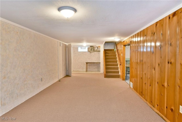 basement featuring wooden walls, carpet, and a textured ceiling