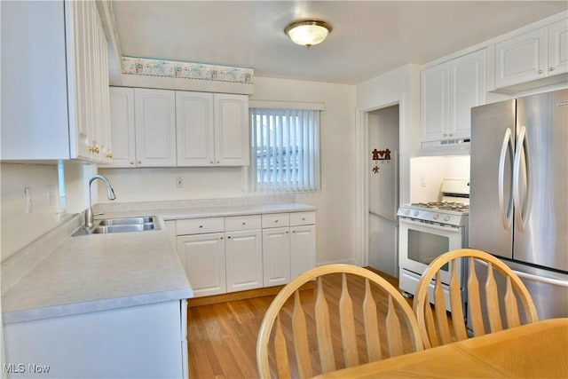 kitchen featuring stainless steel fridge, white gas stove, and white cabinets