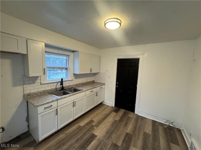 kitchen featuring tasteful backsplash, white cabinetry, and sink