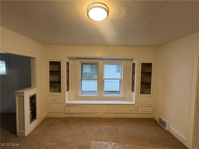 unfurnished living room featuring a healthy amount of sunlight and light colored carpet