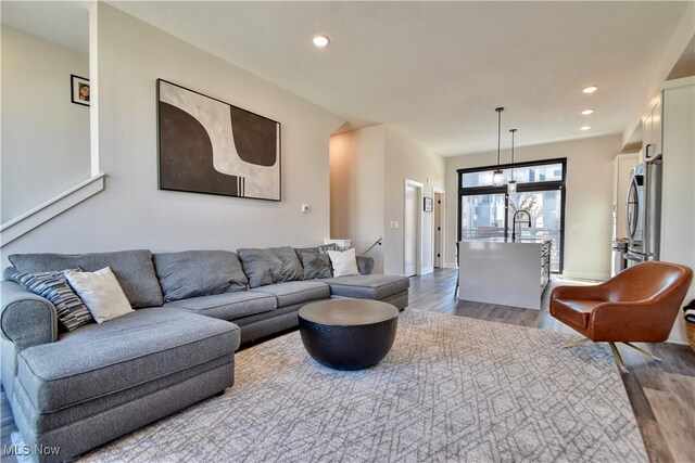 living room featuring baseboards, wood finished floors, recessed lighting, and a chandelier