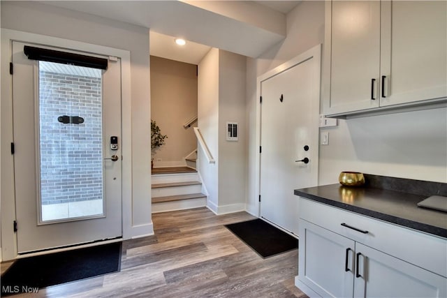 entrance foyer with stairway, baseboards, wood finished floors, and a wealth of natural light