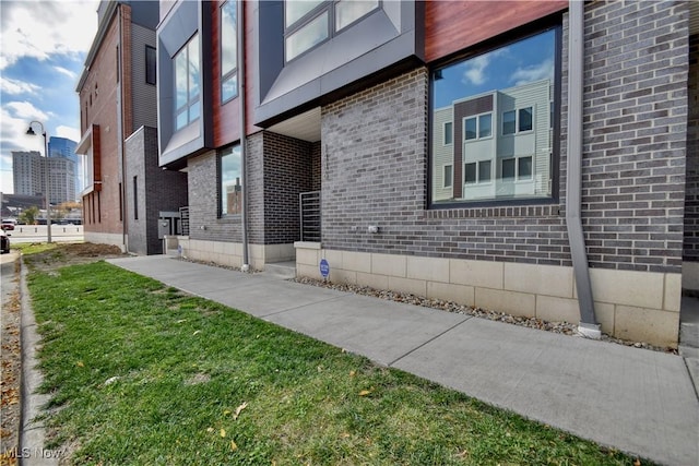 exterior space featuring brick siding and a yard