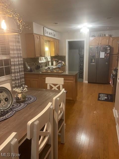 kitchen featuring backsplash, stainless steel fridge, light brown cabinets, and light wood-type flooring