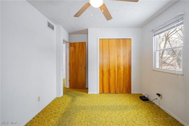 unfurnished bedroom with ceiling fan, a textured ceiling, light carpet, and a closet