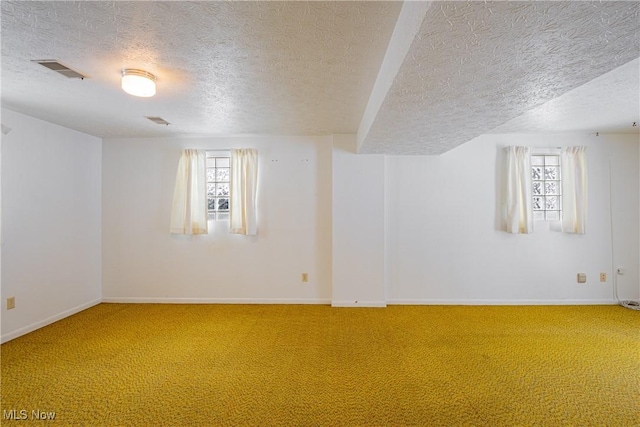 basement featuring carpet flooring, plenty of natural light, and a textured ceiling