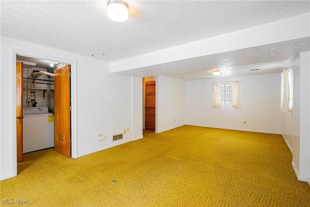 basement featuring light carpet, washer / dryer, and a textured ceiling