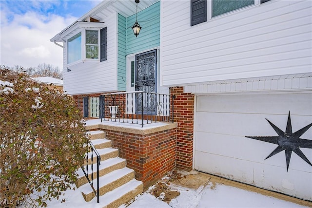 snow covered property entrance featuring a garage