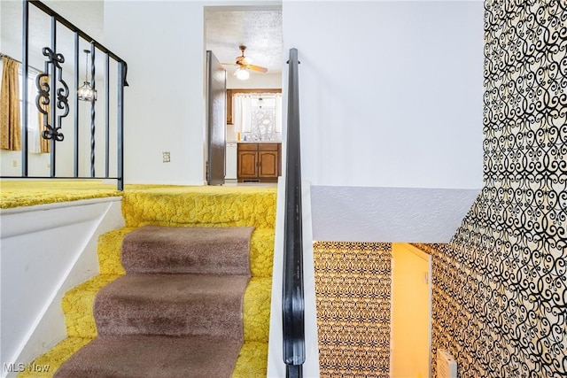 staircase with a textured ceiling and ceiling fan