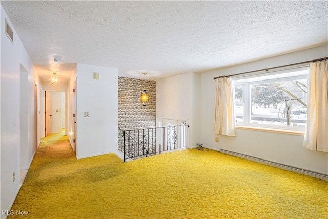 carpeted empty room featuring a textured ceiling and a baseboard heating unit