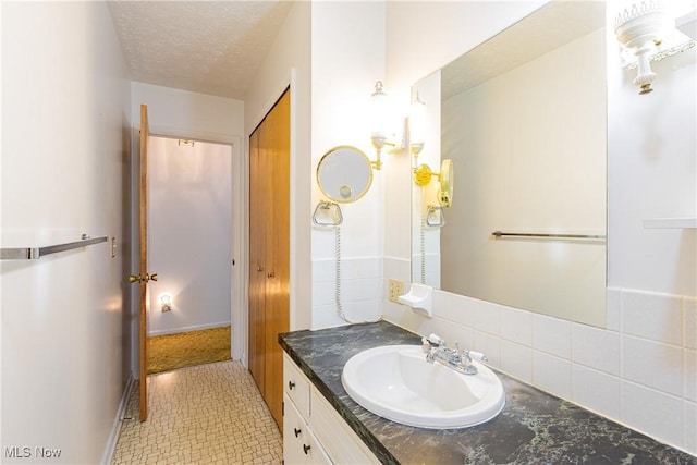 bathroom featuring tile patterned floors, vanity, a textured ceiling, and tasteful backsplash