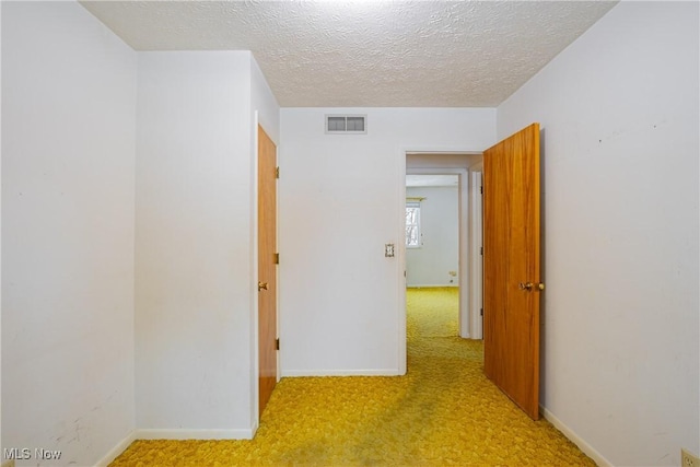 corridor featuring a textured ceiling and light colored carpet