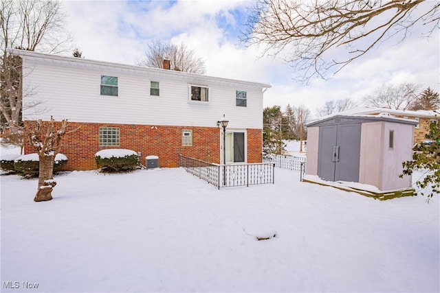 snow covered house featuring a shed