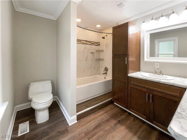 full bathroom with vanity, crown molding, tiled shower / bath, hardwood / wood-style flooring, and toilet