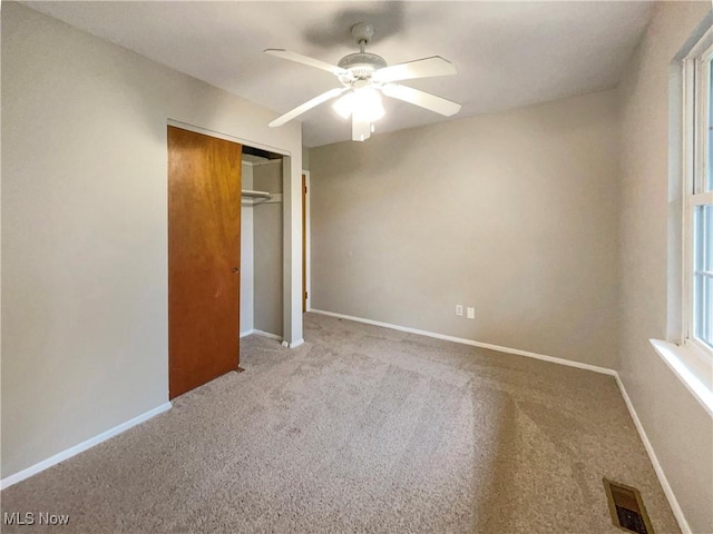 unfurnished bedroom featuring ceiling fan, light colored carpet, and a closet