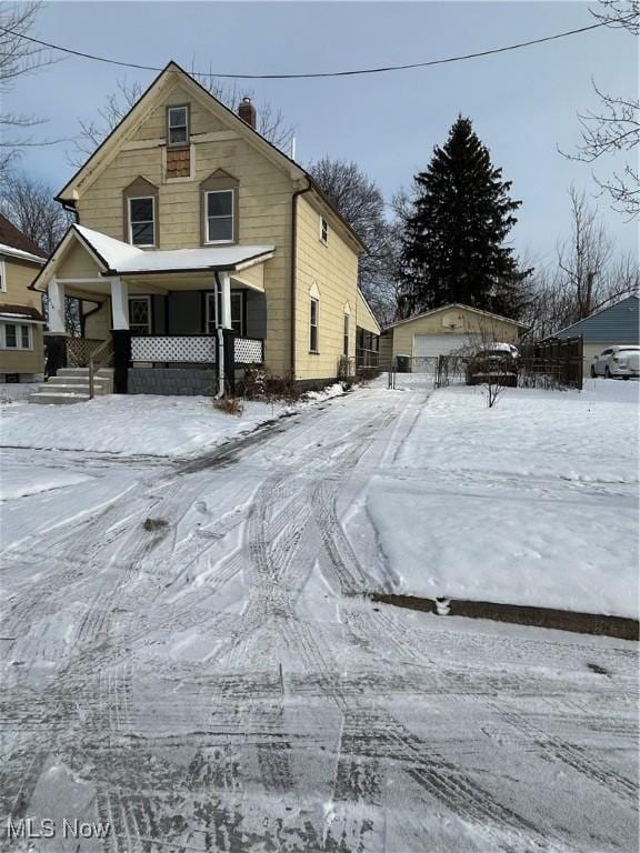 front of property with covered porch, a garage, and an outbuilding