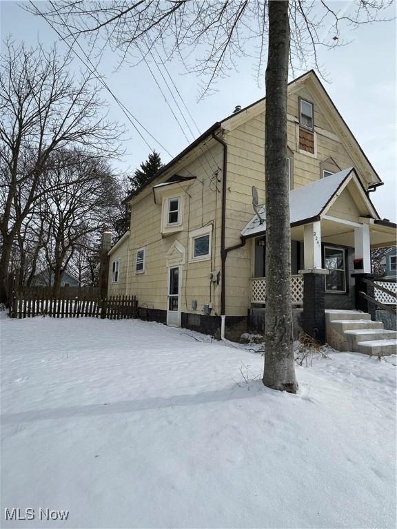 snow covered back of property with a porch