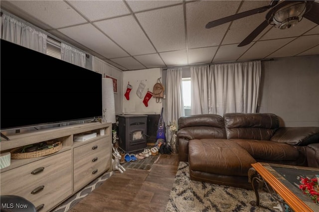 living room featuring a wood stove and a paneled ceiling