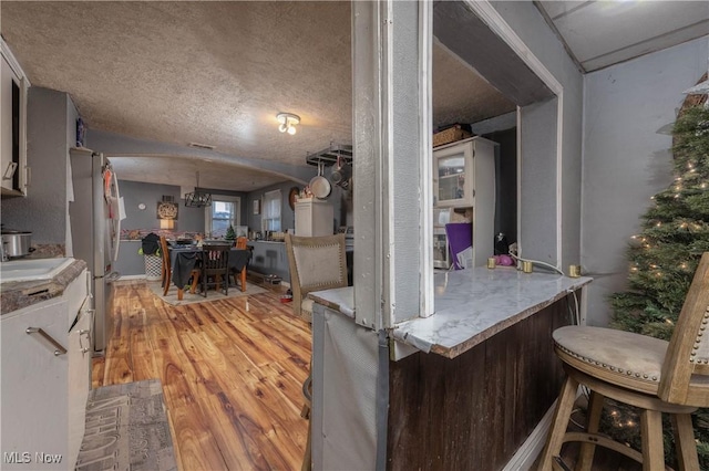 kitchen featuring a textured ceiling, light hardwood / wood-style flooring, and stainless steel refrigerator