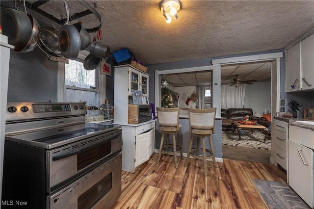 kitchen featuring ceiling fan, light wood-type flooring, white cabinetry, and electric stove