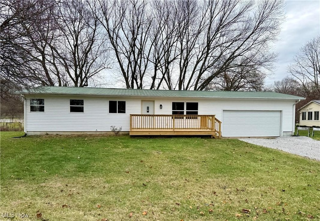 single story home with a wooden deck, a front yard, and a garage