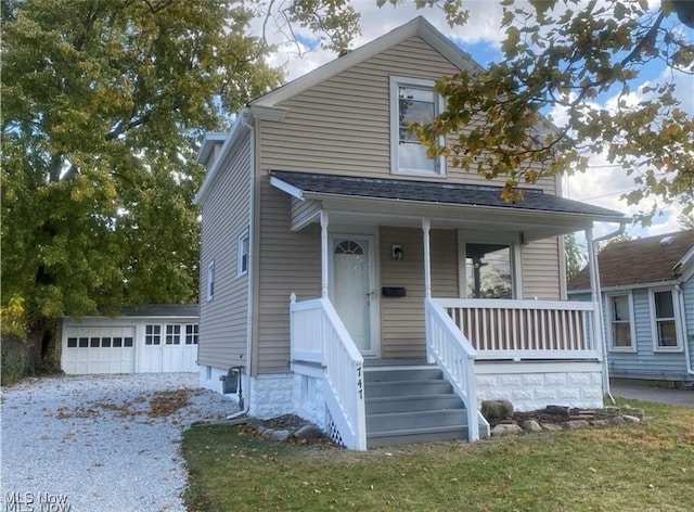 view of front of property with covered porch, a garage, an outbuilding, and a front yard