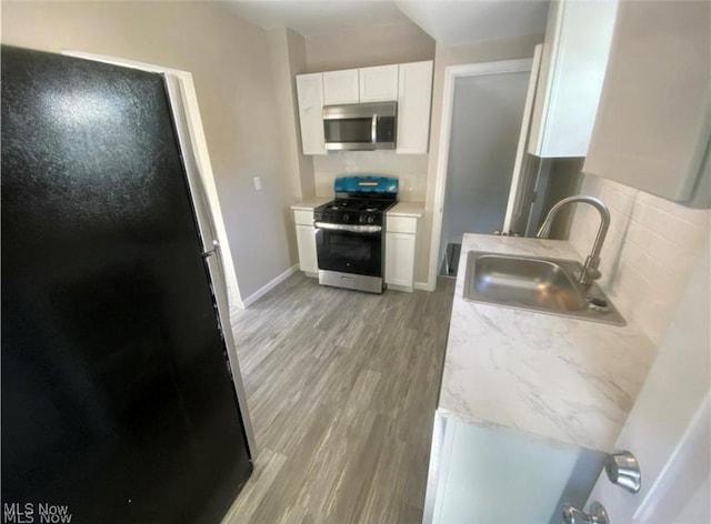 kitchen featuring sink, white cabinetry, stainless steel appliances, and light wood-type flooring